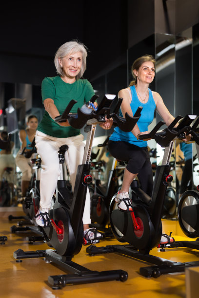 两个成熟的女人在健身自行车上训练图片下载