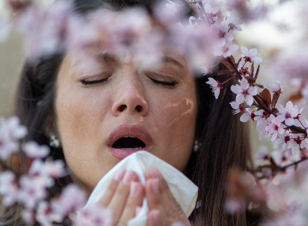 春天，女孩在盛开的树前打喷嚏图片下载