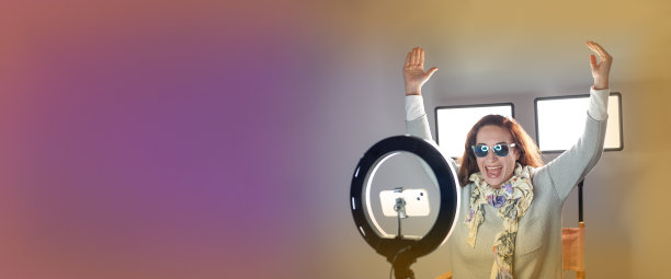 快乐的女网红坐在戒指灯旁使用智能手机图片下载