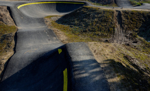 在模块化的泵道轨道上，使用泵(上下移动)代替踏板和弹跳来移动自行车、滑板、滑板和直排旱冰鞋图片下载