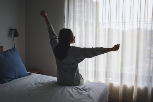 一个女人在卧室醒来后做伸展的后视图图像图片下载