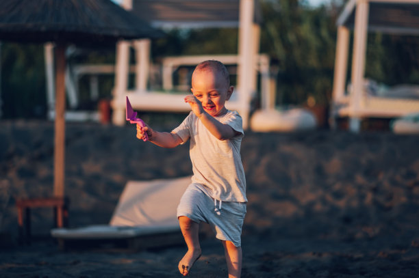 一个赤脚快乐的小男孩笑着在沙滩上跳跃图片下载