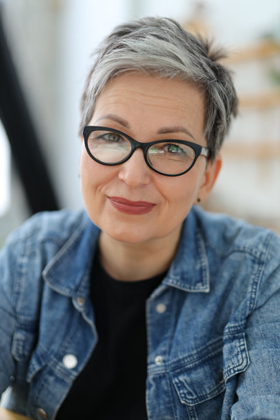 一个积极的成年女性的肖像在眼镜，牛仔布。图片下载