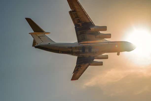 一架飞机在天空中飞行，太阳在它后面。图片下载