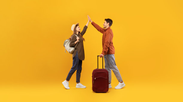 快乐的旅行者夫妇在黄色背景下击掌图片下载