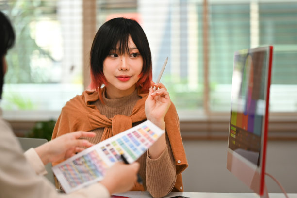 年轻漂亮的亚洲女性与她的同事在创意工作场所合作新的创业项目。图片下载