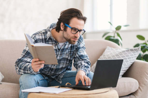 戴眼镜的白人学生集中认真聪明的年轻男子看笔记本电脑，查找错误图片下载