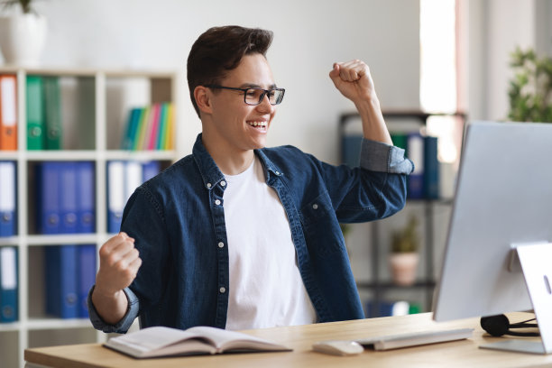 快乐的年轻企业家在办公室看着电脑屏幕庆祝成功图片下载