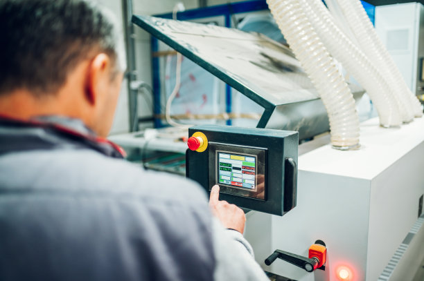 操作人员调整家具加工机器的后视图。图片下载