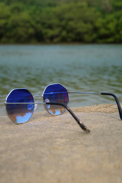 图像对八角形，金属框架，着色，镜面太阳镜展开臂在潮湿的海滩沙滩，海岸背景的海洋和林地棕榈树，后视图，重点在前景，复制空间图片下载