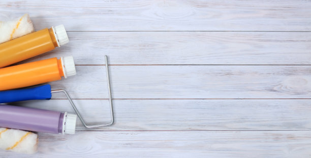 木桌上的丙烯酸漆罐和漆辊，俯视图。修理或油漆用材料图片下载