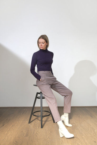 一系列的工作室照片，年轻的女模特穿着舒适的基本装备，粘胶合身的高领衬衫和基本的香烟裤图片下载