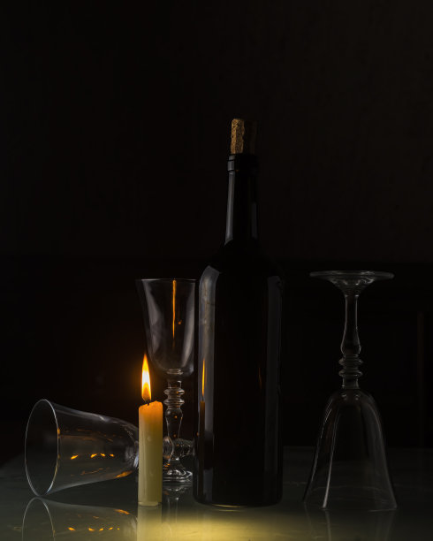 一瓶打开的葡萄酒和空的干净杯子放在磨砂玻璃桌上，蜡烛在柔和的气氛中图片下载