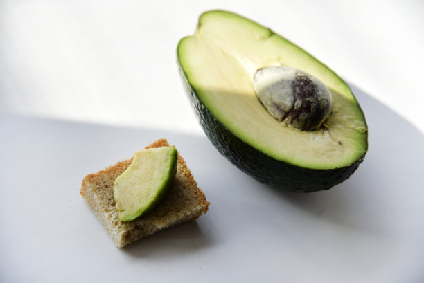 绿色的牛油果在白色的背景上切成片。白盘子里的牛油果。牛油果切片和半块图片下载