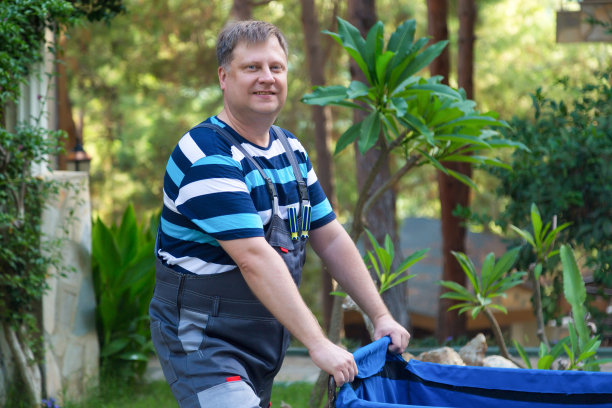 在城市街道上，一个人推着垃圾收集车图片下载