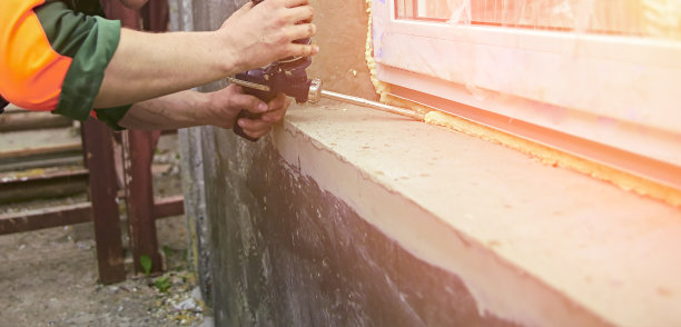 一名建筑工人将密封泡沫胶带粘在房子的窗户上。图片下载