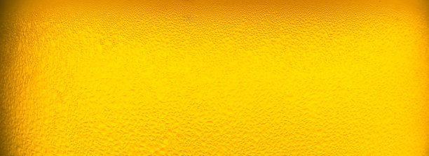 宏观啤酒玻璃背景，在玻璃中倒入带有泡沫的啤酒作为背景和设计。图片下载