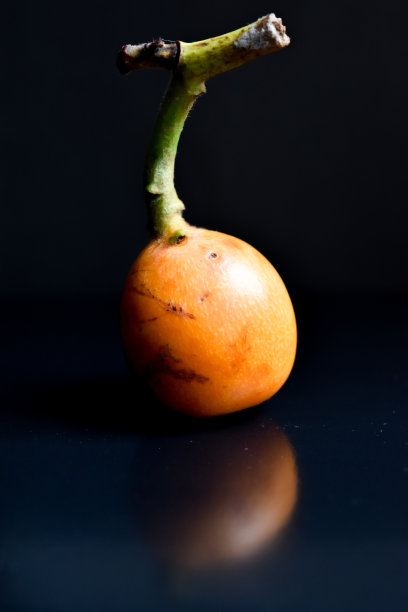 在黑色的桌子上放着一个亮黄色的菠萝水果，背景是黑色的。图片下载