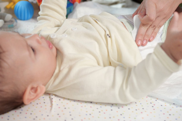 妈妈在桌子上给婴儿换尿布，特写图片下载