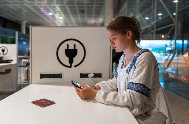 女孩晚上在机场给手机充电。图片下载