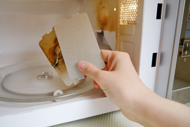 通过更换云母板修复一个闪闪发光的微波炉。坏了的微波炉，可自行更换烧焦的云母片图片下载