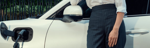 近景:进步的女商人在充电站拿着电动汽车。图片下载