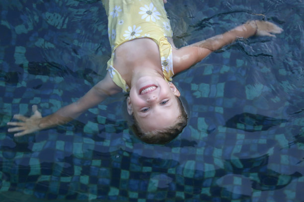 可爱的5岁小女孩漂浮在游泳池里的照片图片下载