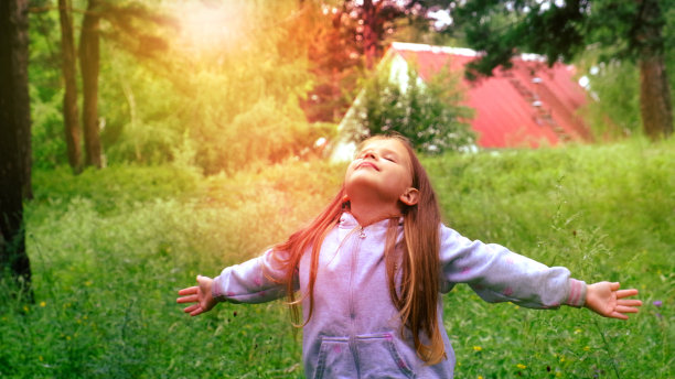 草地上的小女孩举起双手，深呼吸。雨后的森林，空气清新。享受生活图片下载