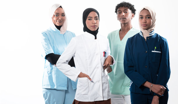 一群混合年龄的医生和护士并肩站在一起，看着镜头的特写镜头。年轻的中东女性和非裔美国男性医生在一个小组。图片下载