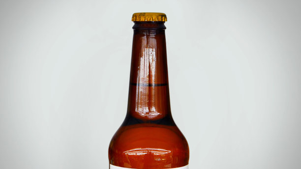 白色背景下漂亮的棕色啤酒瓶特写图片下载