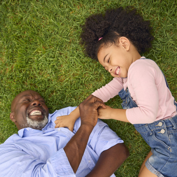外祖父和外孙一起在花园草地上微笑玩耍的俯拍照片图片下载