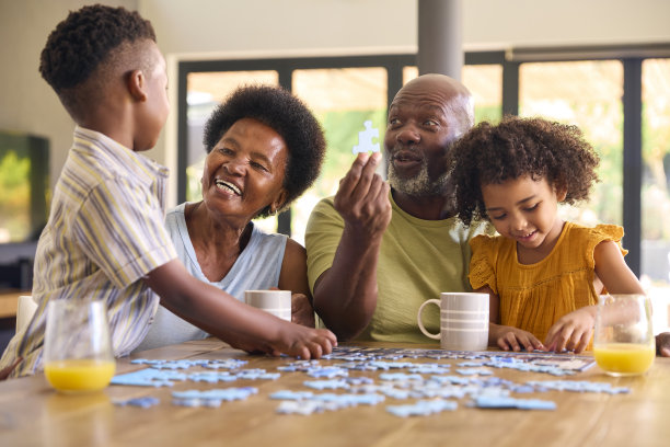 家庭照片，祖父母和孙子在家里的桌子上玩拼图游戏图片下载