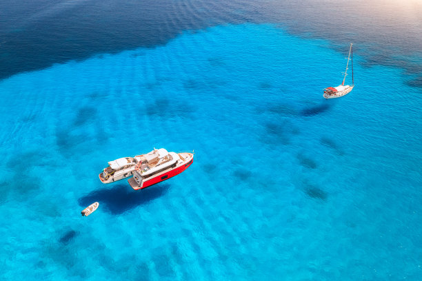 夏日日落时豪华游艇在蓝色海面上的鸟瞰图。意大利撒丁岛。从上面看快艇，游艇，海泻湖，海岸，透明的水。无人机俯视图。热带海景图片下载