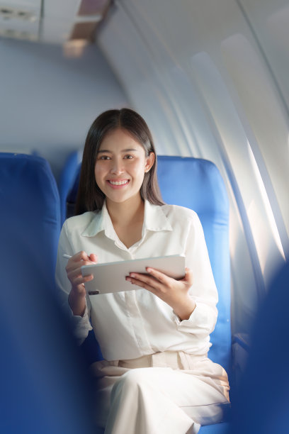 美丽的亚洲女商人在飞机上用数码平板电脑工作。工作、旅游、创业理念图片下载