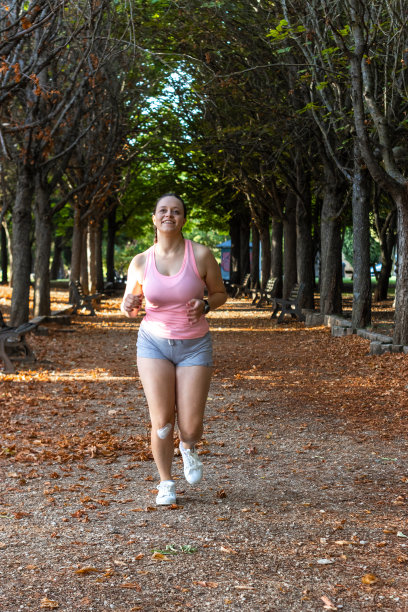 迷人的运动女人在公园里向前奔跑。美丽的运动女孩在公园里跑步的正面照片。在公园里跑步的人图片下载