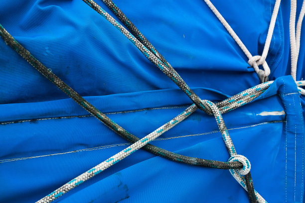 在蓝色帆布上，绳子在中间打结，特写。用绳子在帆布上打的航海结。图片下载