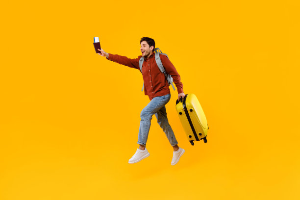 跳伞的游客拿着护照、车票和行李箱，黄色背景图片下载