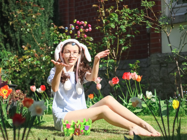 一个白人少女坐在草坪上扔复活节巧克力蛋的照片。图片下载