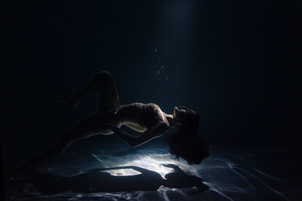 水下拍摄美丽的女人游泳和放松的水在阳光下。图片下载