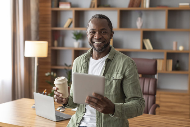 开朗英俊成熟的黑人商人拿着平板电脑和一杯外卖饮料看着镜头图片下载