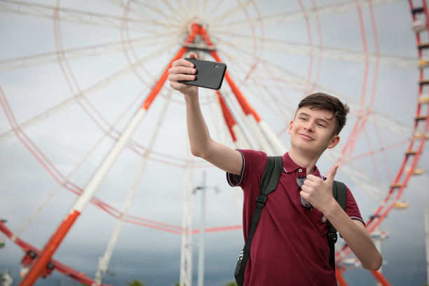 十几岁的男孩在户外摩天轮附近自拍。文本空间图片下载