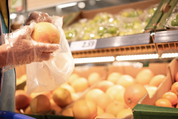 老年男子的手挑选葡萄柚或橙子在超市购物杂货挑选水果注意成本和质量-消费主义观念，价格上涨，通货膨胀图片下载