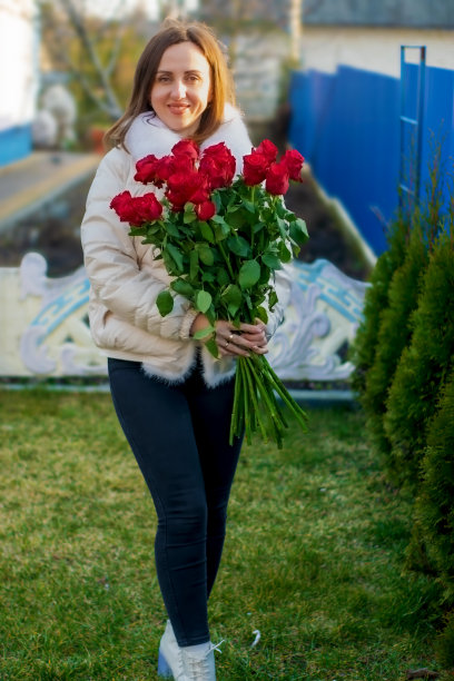 一个穿着温暖的白色夹克的女孩拿着玫瑰花。图片下载