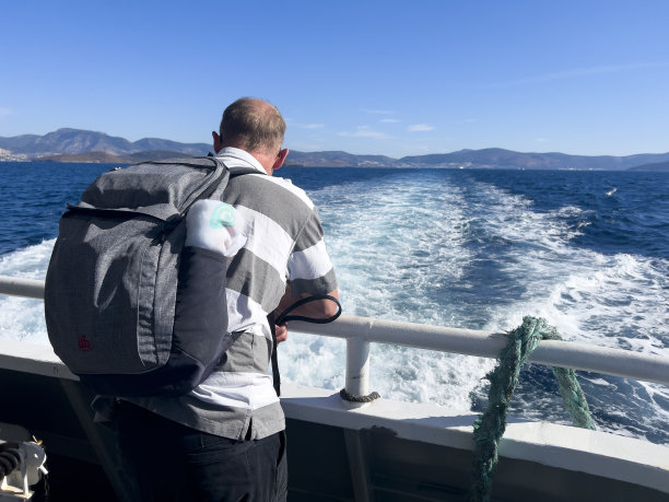 一个孤独的人站在船尾的栏杆上，后视图图片下载