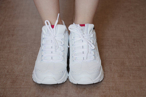 一个站在地板上的女孩裤脚里塞着一双白色运动鞋图片下载
