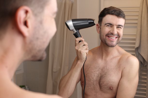 英俊的男人在吹他的头发图片下载