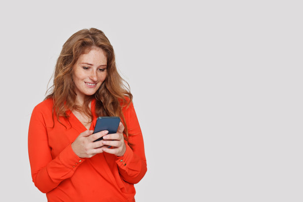 迷人的开朗的女人在白色的工作室墙壁背景上发短信图片下载