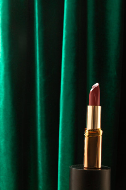 一只口红在绿色天鹅绒布料的背景。圣诞节模拟，模板或海报广告口红。图片下载