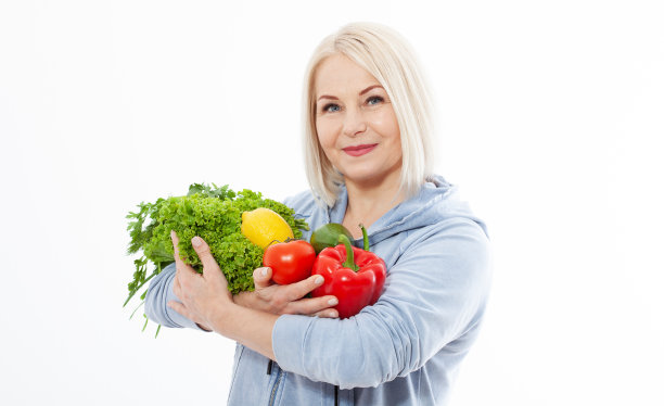 快乐的女人，金色的头发和美丽的微笑拿着蔬菜和香草，红辣椒和绿色的生菜在她的手为健康的饮食。健康吃蔬菜的概念。图片下载