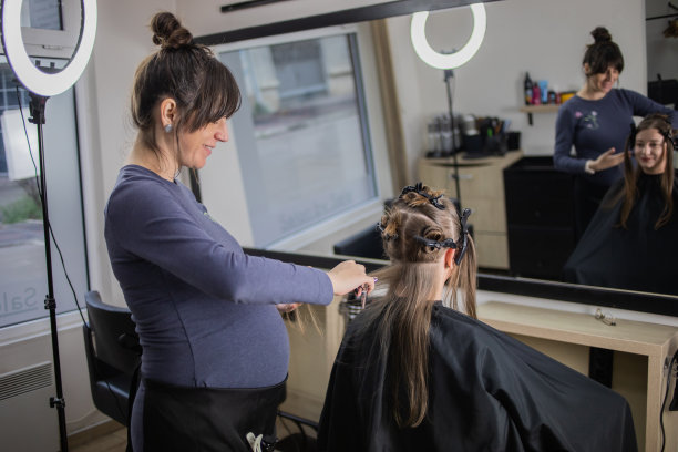 一位年轻的孕妇在美容院工作。图片下载